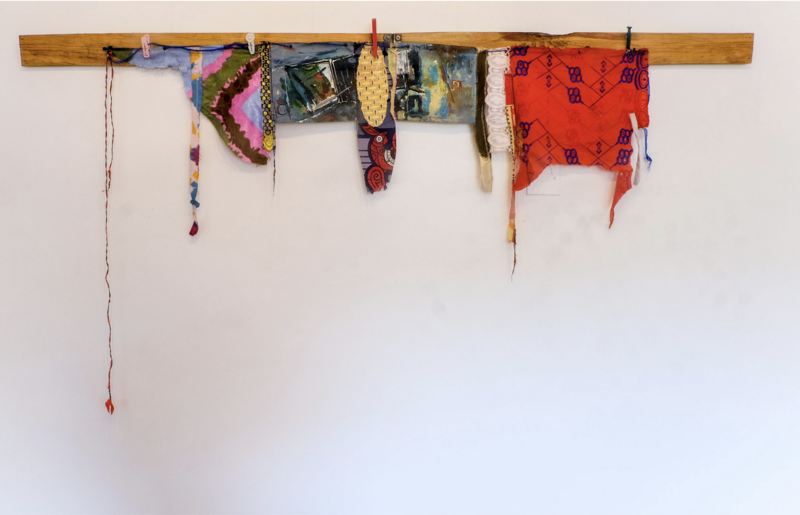 Installation artwork titled Substance and Emptiness (2004-2015) by Amarachi Okafor, measuring 99 x 194.5 cm. The piece features a horizontal wooden beam with various fabric scraps, woven materials, and painted elements hanging from it.